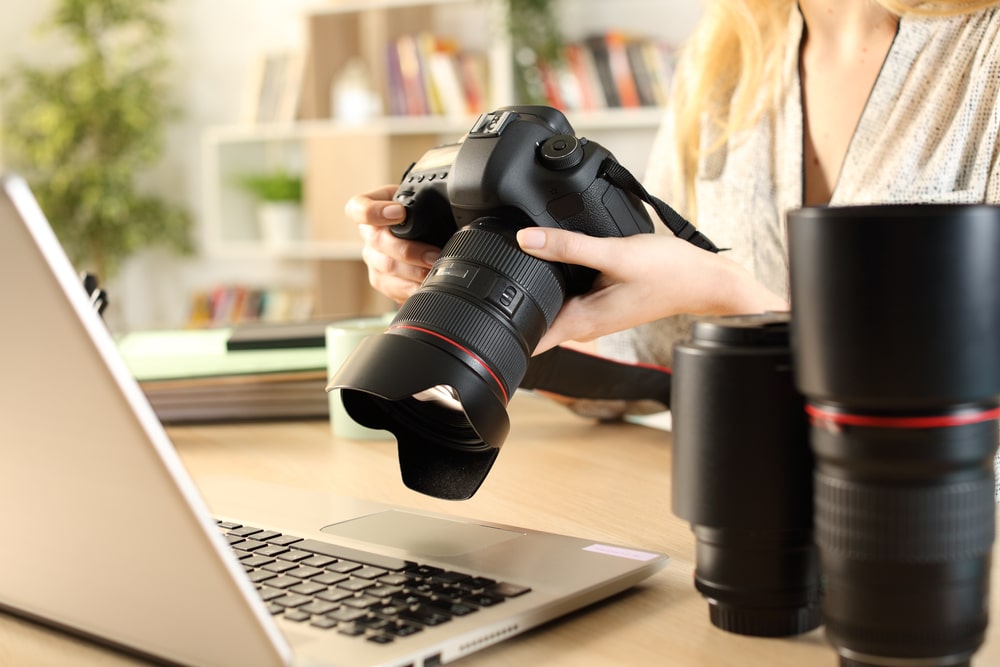 Close up of photographer woman hands with laptop checking dslr
